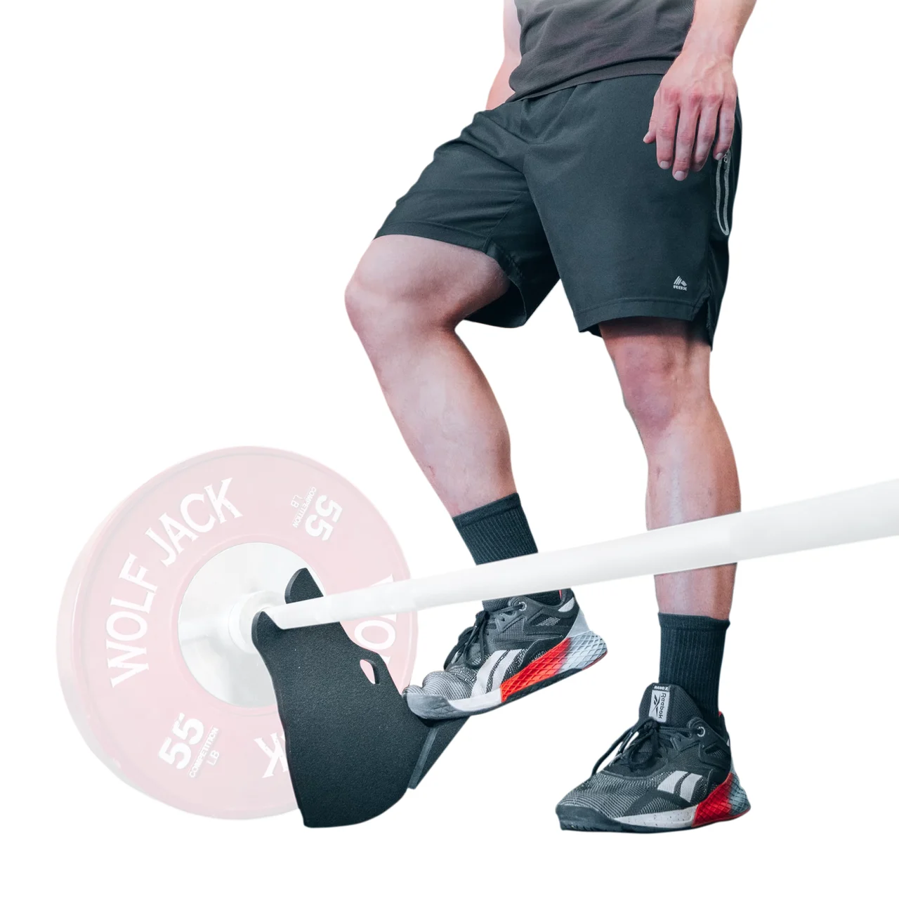 A lifter operating Wolf Jack with a foot while a loaded barbell rests above the floor